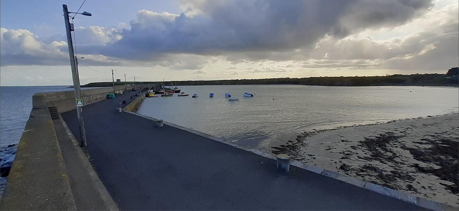Loughshinny pier with small boats and the beach at evening
